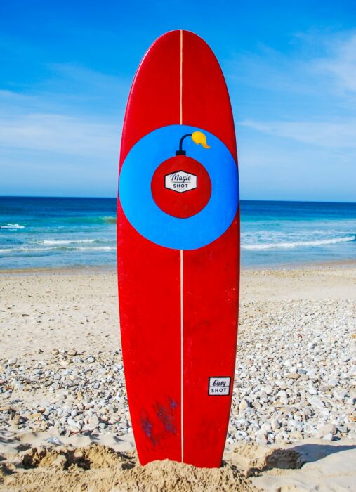 Red surfboard with a life ring standing in the sand at the beach